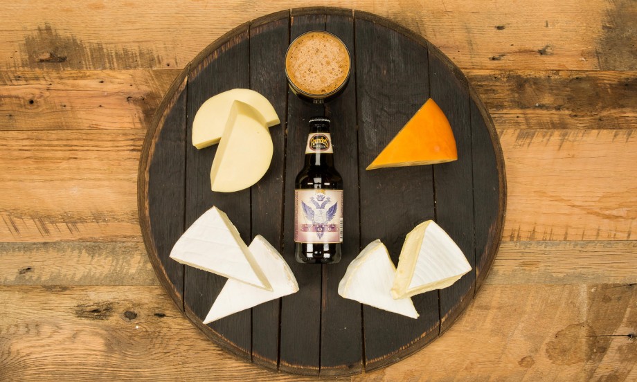 Wooden platter with Imperial Stout and different cheeses