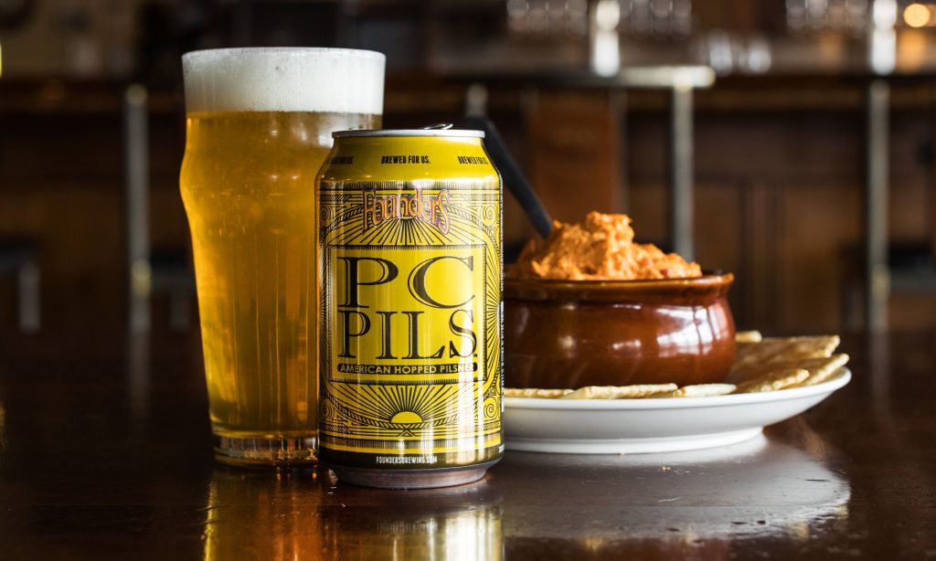 Can and glass of Founders Pc Pils and plate of crackers and dip