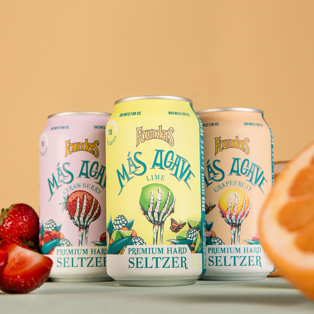 three cans of mas agave seltzer with fruit in foreground