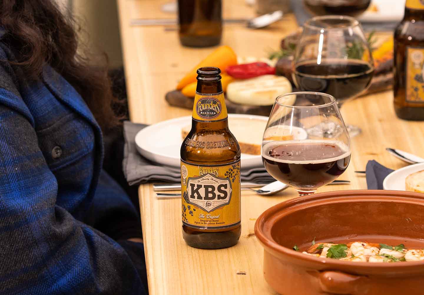 Bottle of KBS on table with snifters and food
