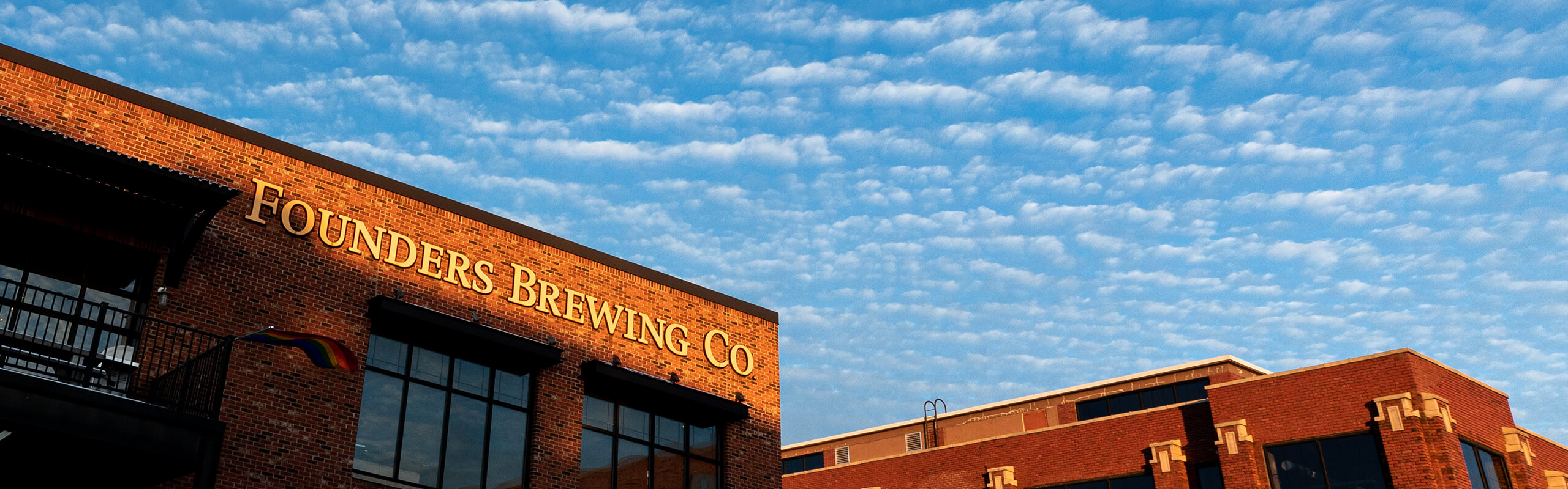Exterior of Founders Brewing Co. building in sunlight with blue sky